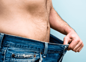 man wearing jeans pulling them away from waist to show weight loss