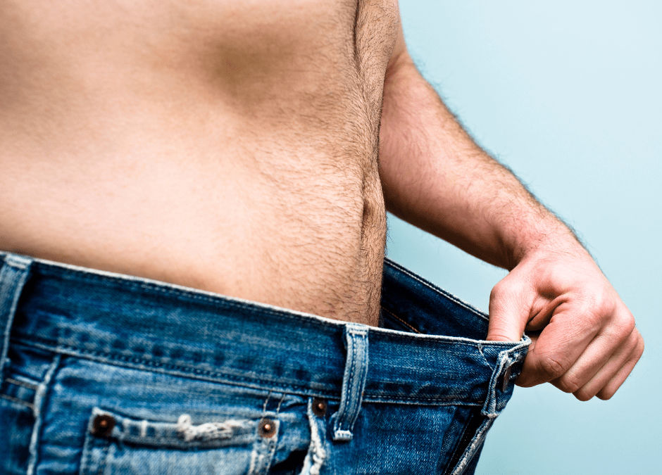 man wearing jeans pulling them away from waist to show weight loss