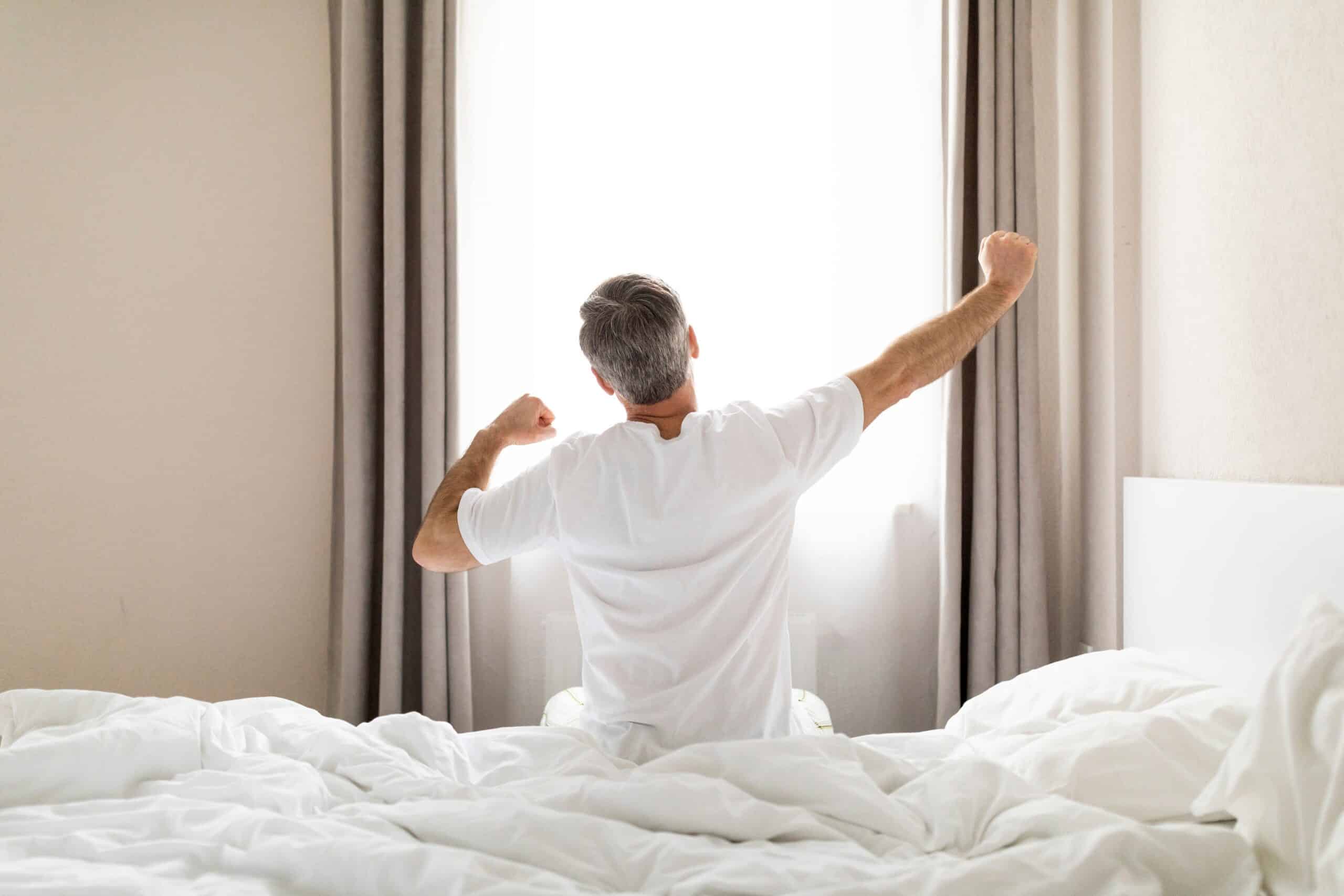 TRT and sleep quality improvement — man stretching after a restful night's sleep